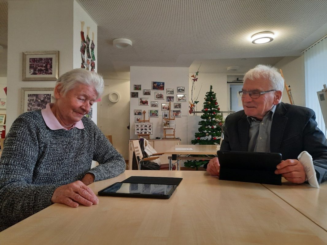 Zwei ältere Menschen sitzen vor einem Tablet