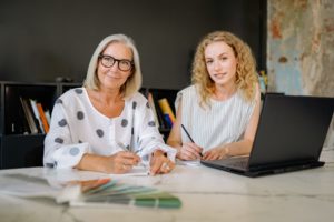 Zwei Frauen sitzen an einem Tisch vor einem Laptop