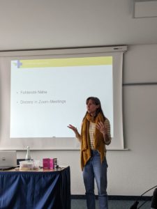 Die Referentin steht vor der Powerpoint Präsentation und spricht zu den Teilnehmenden