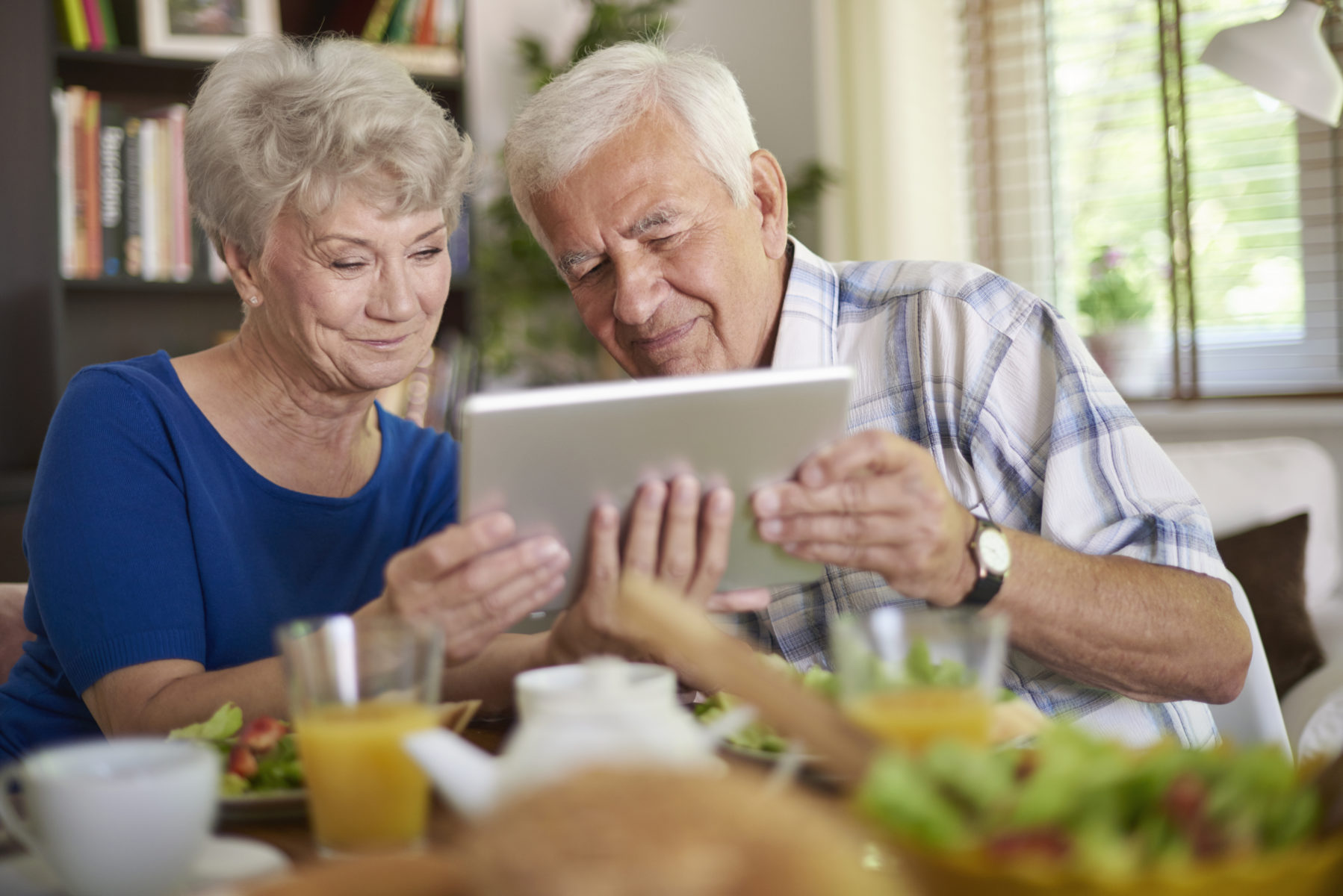 Zwei ältere Menschen blicken gemeinsam in ein Ipad