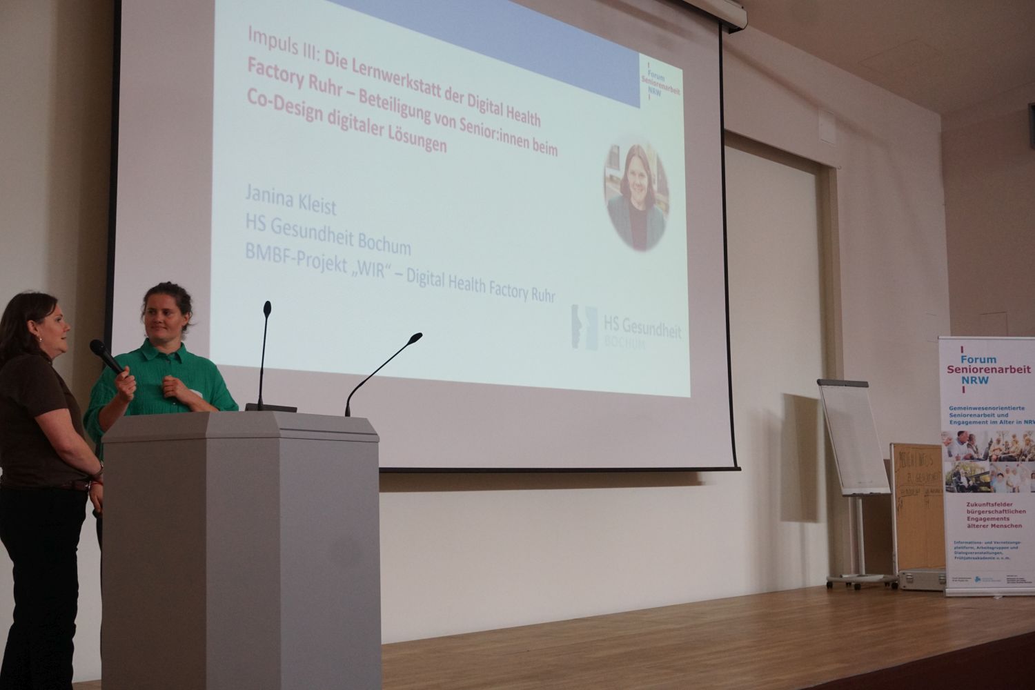 Das Foto zeigt die Referentin Janina Kleist mit der Projektleitung des Forum Seniorenarbeit NRW, Christine Freymuth, vor der Powerpoint Präsentation stehend